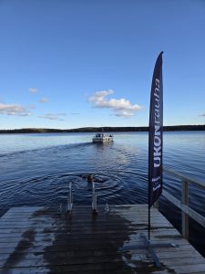 Haapasaaren laituri, ihminen uimassa ja kauempana vene seilaamassa.
